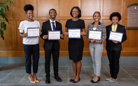 Five individuals in business attire, proudly displaying award certificates at Weill Hall.