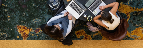 Top-down view of two students working on their laptops at a table