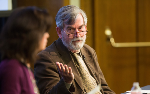 Two individuals engaged in a discussion at a formal event, one of whom is gesturing while speaking.