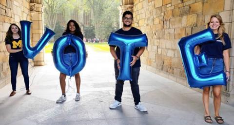 Photo of students holding letter-shaped balloons that spell out "Vote"